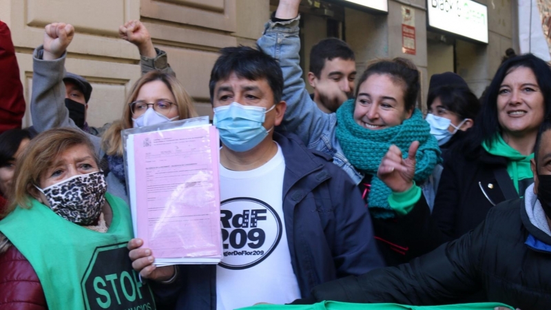 El Carlos, envoltat d'activistes pel dret a l'habitatge, mostrant el paper de suspensió del desnonament que l'afectava, aquest 3 de desembre de 2021.