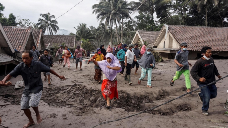 La gente inspecciona su aldea enterrada con ceniza volcánica de la erupción del monte Semeru en la aldea de Sumber Wuluh en Lumajang