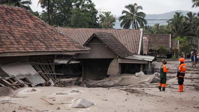 Los equipos de rescate se paran cerca de las casas enterradas en ceniza volcánica de la erupción del monte Semeru en Lumajang