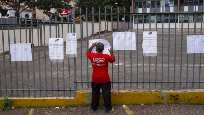 Un hombre busca su nombre en las hojas del padrón electoral a la entrada de un colegio electoral durante las elecciones regionales y municipales en Caracas, el 21 de noviembre de 2021.