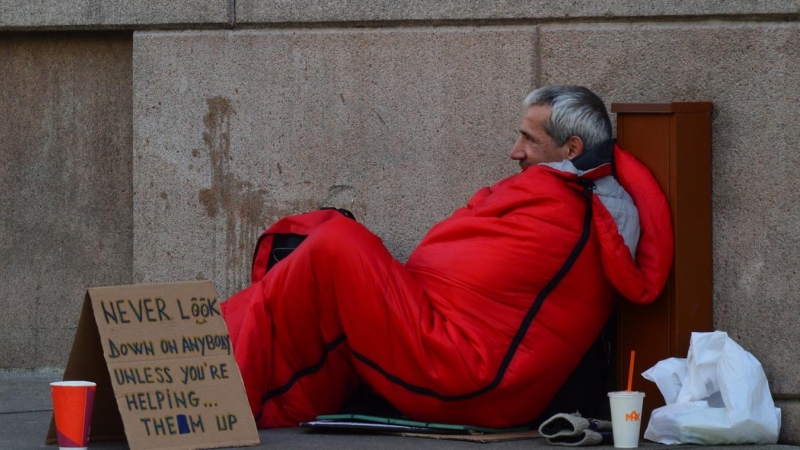 Una persona sin hogar pidiendo en la calle.