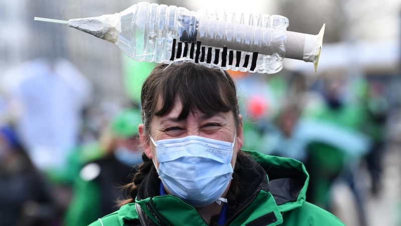 Una trabajadora de la salud lleva un elemento simbólico en forma de jeringa en la cabeza mientras participa en una manifestación sindical contra la vacunación obligatoria, en Bruselas el 7 de diciembre de 2021.