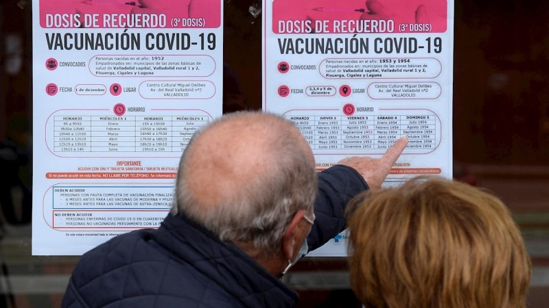 Dos personas observan un cartel con las pautas para recibir la tercera dosis de Pfizer en Valladolid este miércoles en el que el Ministerio de Sanidad ha recomendado limitar el número de participantes en los 'eventos públicos y sociales', especialmente