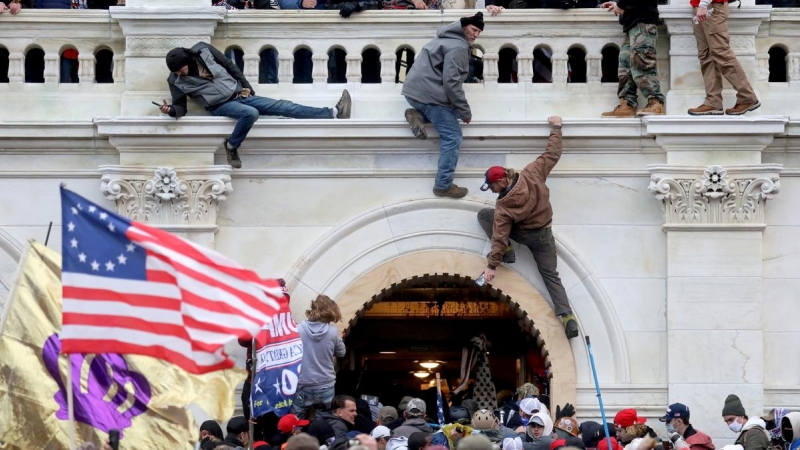 Partidarios del expresidente de Estados Unidos, Donald Trump, se pelean con miembros de las fuerzas del orden en una puerta que rompieron mientras irrumpen en el edificio del Capitolio de Estados Unidos, en Washington, Estados Unidos, el 6 de enero de 202