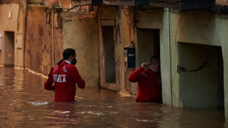 Trabajadores de Protección Civil caminan por una calle inundada, a 12 de diciembre de 2021, en Tudela, Navarra.