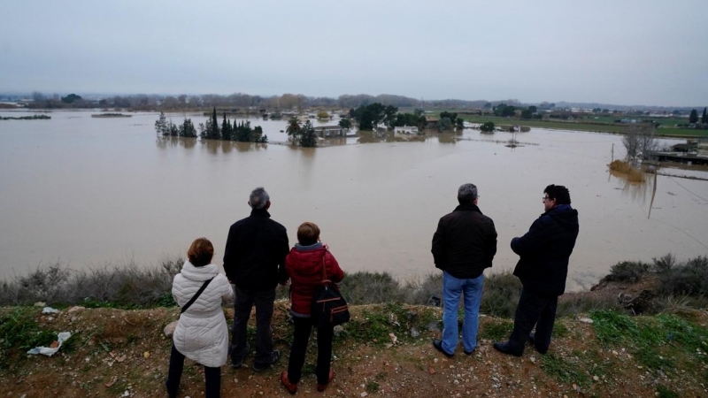 Varias personas observan los edificios de una granja sumergidos después de fuertes lluvias e inundaciones en Zaragoza. REUTERS / Vincent West