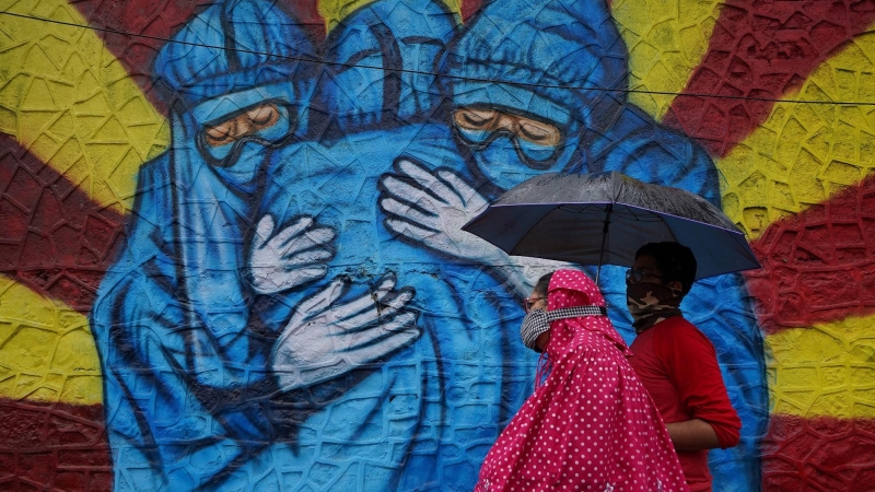 Una mujer y su hijo pasan frente a un graffiti en Mumbai, India.