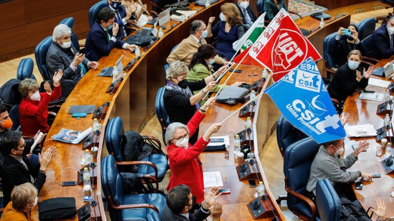 Diputados con banderas sindicales durante una sesión plenaria en la Asamblea de Madrid, a 22 de diciembre de 2021, en Madrid.