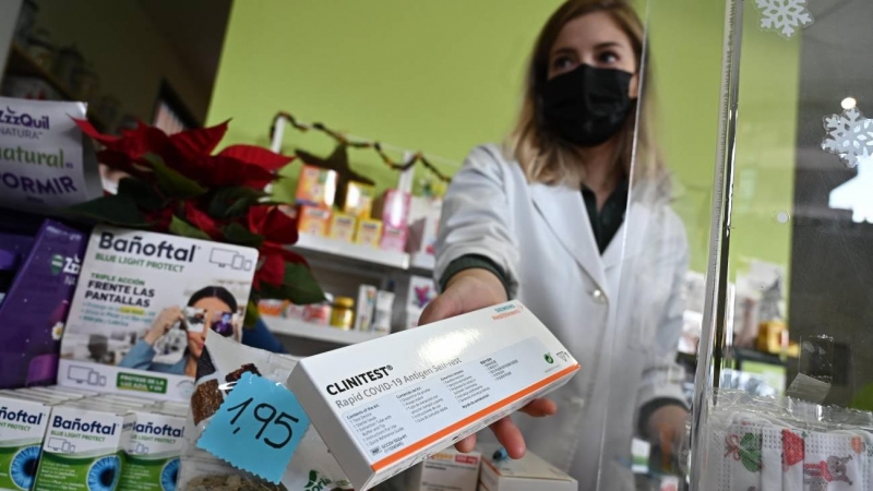 Una farmacéutica muestra el último test de antígenos que tiene disponible a la venta en su farmacia de Madrid