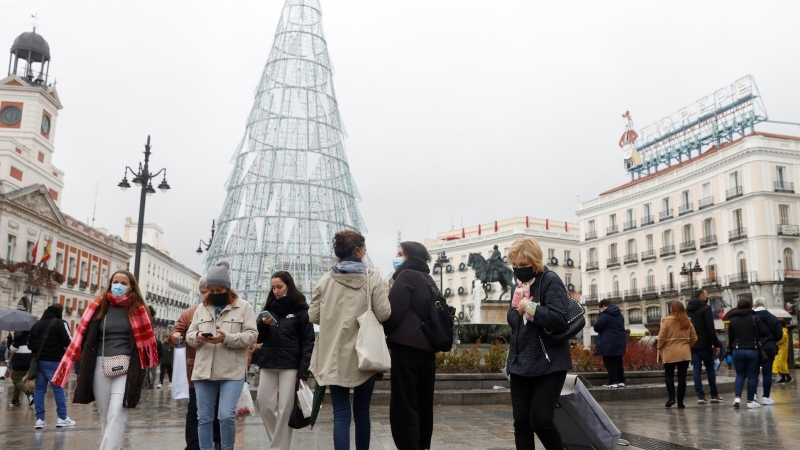 Varias personas caminan con mascarillas por la Puerta del Sol este viernes 24 de diciembre de 2021, día de Nochebuena.