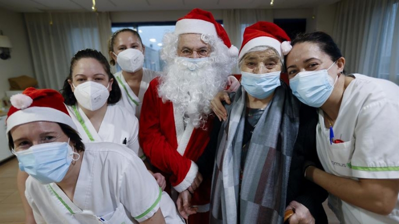 Nicosio, (4i) y Lola (5i) posan con trabajadores de la residencia Domus VI el día de Nochebuena, antes de repartir caramelos en el centro, donde disfrutan de la visita de familiares, menú especial navideño y actividades para sobrellevar la sexta ola del c