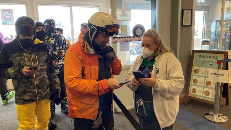 Una trabajadora de la estación de esquí de Sierra Nevada solicita el certificado covid a las personas que entran.