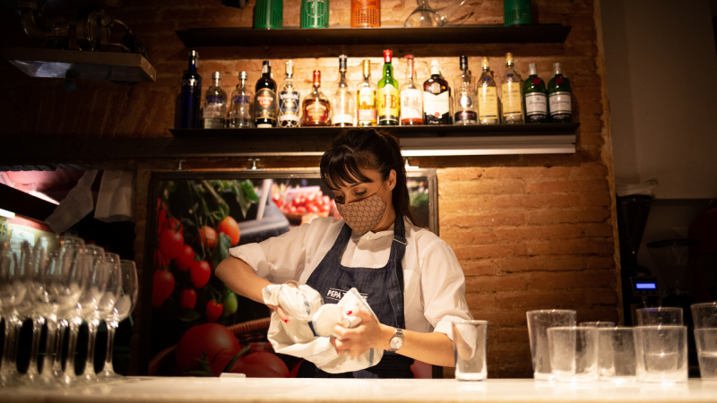 Una camarera seca unos vasos en el interior de un bar en una calle céntrica de Barcelona, a 14 de octubre de 2021, en Barcelona, Catalunya.