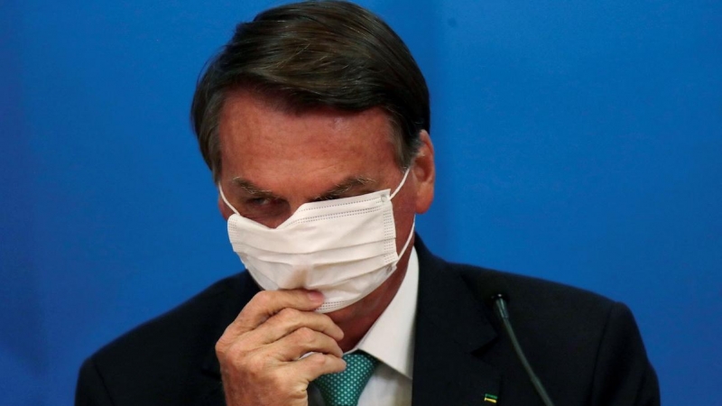 El presidente de Brasil, Jair Bolsonaro, ajusta su mascarilla protectora durante la ceremonia de firma del Acuerdo de Transferencia de Tecnología de Vacunas, en Brasilia, a 1 de junio de 2021.