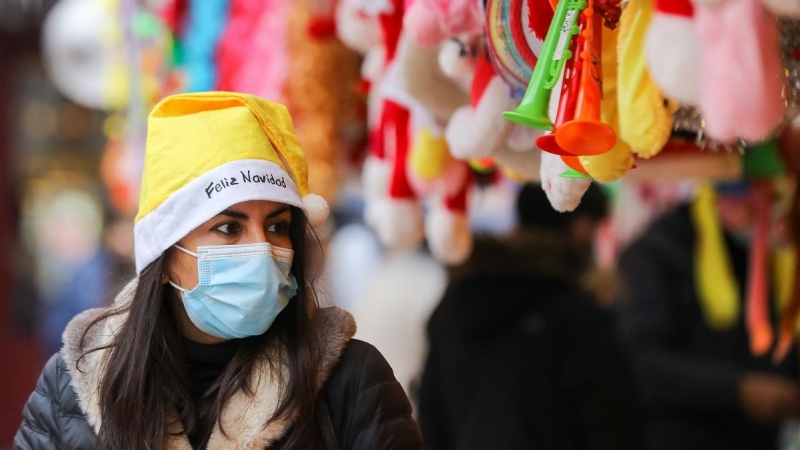 Una mujer con un gorro de Papa Noel y una mascarilla, el mismo día que entra en vigor la obligatoriedad de usar mascarilla en exteriores, a 24 de diciembre de 2021, en Madrid.