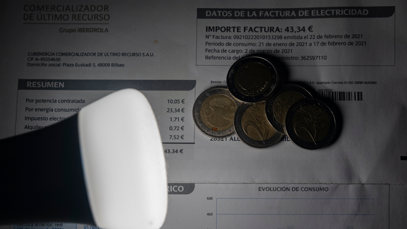 Una lámpara refleja el importe de una factura el día en que el precio de la luz ha marcado un mínimo por primera vez en dos meses, a 27 de diciembre de 2021, en Madrid.