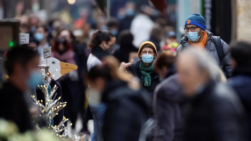 Personas, con máscaras protectoras, caminan por la calle Mouffetard, en medio de la propagación de la pandemia en París, Francia, 30 de diciembre de 2021.