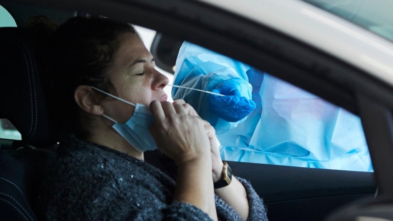 Una sanitaria le realiza la prueba PCR a una mujer en su coche durante la realización de PCR en el autocovid instalado en el Hospital Militar, a 28 de diciembre de 2021 en Sevilla.