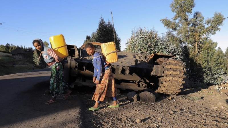 07/12/2021 Civiles pasan junto a un tanque militar destruido en los combates entre la Fuerza de Defensa Nacional de Etiopía (ENDF) y el TPLF