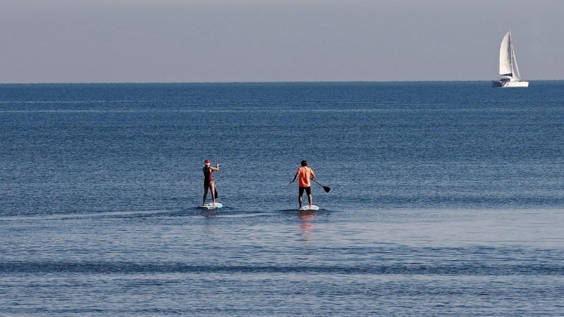 Dos personas practican paddel surf en la playa de la Malvarrosa de Valencia en el que los cielos en la Comunitat Valenciana durante el primer día de 2022 serán predominantemente poco nubosos o despejados y se esperan temperaturas altas y bancos de niebla