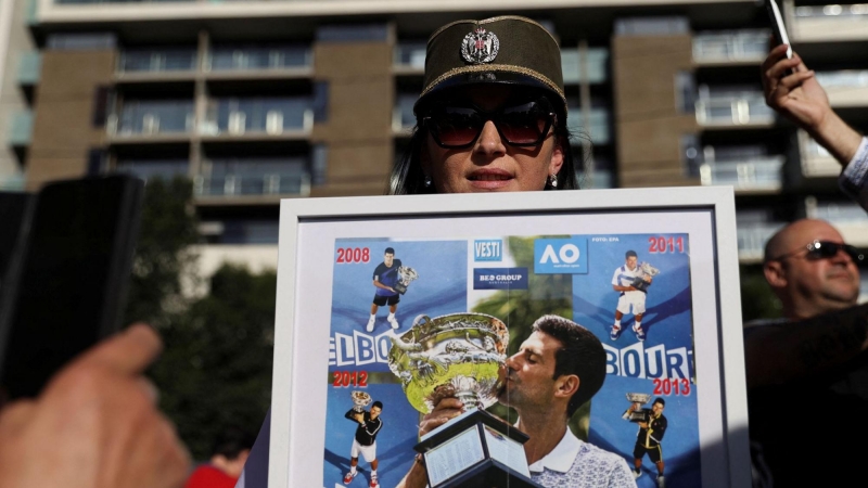 Una mujer sostiene un montaje con las victorias de Djokovic en el Open de Australia a las afueras del tribunal que ha decidido dejarle en libertad en Melbourne este lunes 10 de enero de 2022.