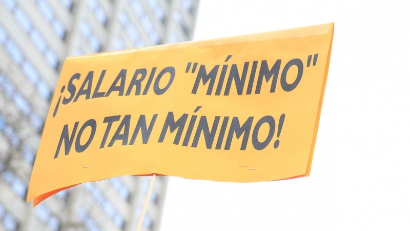 Una mujer, que no aparece en la imagen, sostiene una pancarta donde se puede leer “¡Salario mínimo, no tan mínimo!” como signo de protesta en la concentración convocada frente al Ministerio de Asuntos Económicos, en Madrid. E.P.