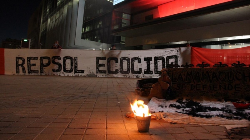 Varios manifestantes sujetan un telar con la bandera de Perú con el lema inscrito 'Repsol Ecocida'.