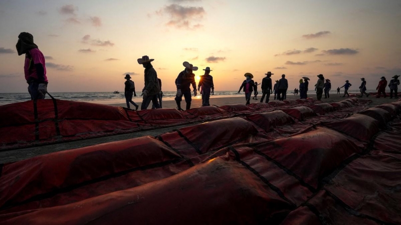 Un grupo de trabajadores trata de bloquear el derrame de petróleo causado ​​por una fuga de un oleoducto submarino a 20 km de la costa este de Tailandia en la playa de Mae Ramphueng, provincia de Rayong, a 28 de enero de 2022.