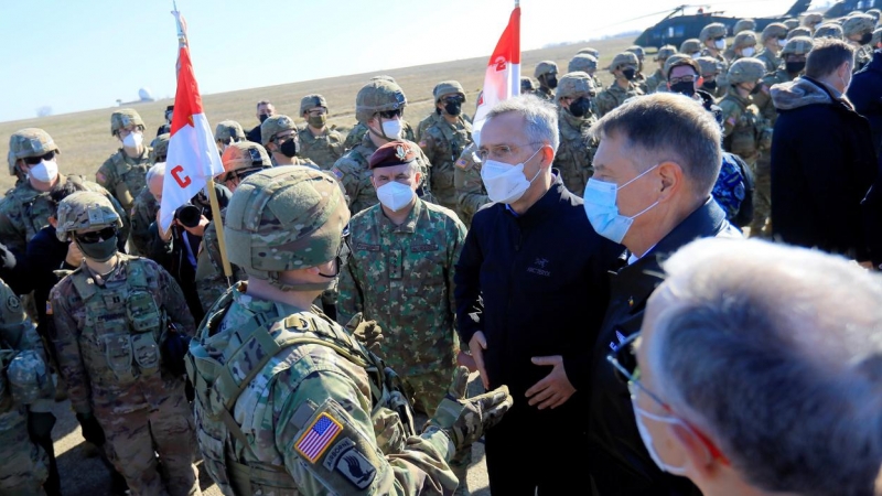 El secretario general de la OTAN, Jens Stoltenberg (C), y el presidente de Rumania, Klaus Iohannis (D), hablan con un oficial al mando de EE. UU. en la base aérea militar de Mihail Kogalniceanu, Rumania, el 11 de febrero de 2022.