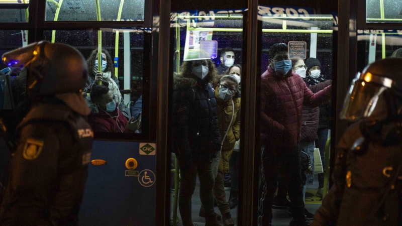 Usuarios del autobús urbano observan el despliegue policial para ejecutar el desalojo del matrimonio octogenario en Madrid.