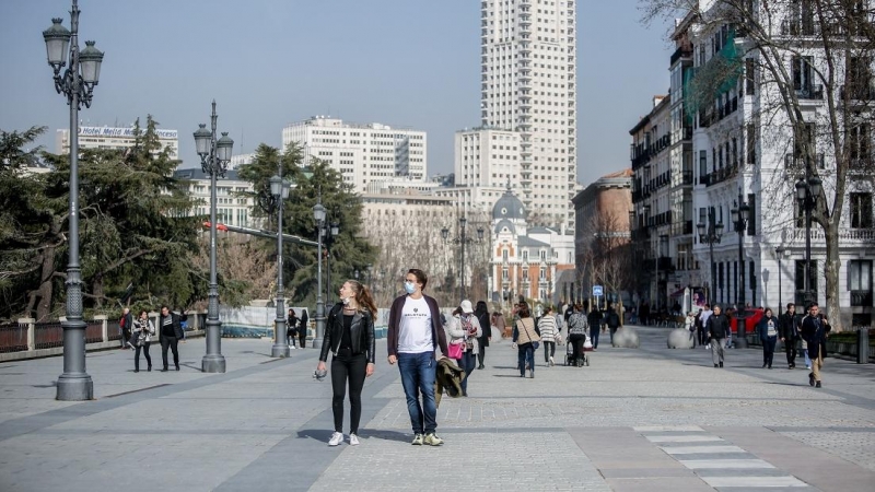 Una mujer camina sin mascarilla y un hombre con mascarilla, a 10 de febrero de 2022, en Madrid