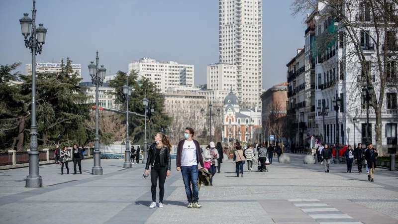 Una mujer camina sin mascarilla y un hombre con mascarilla, a 10 de febrero de 2022, en Madrid