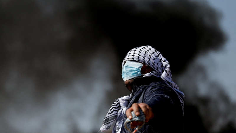 18/02/2022 Un manifestante con el rostro cubierto mira durante una protesta contra los asentamientos judíos en la aldea de Beta, cerca de Naplusa, en la Cisjordania ocupada por Israel
