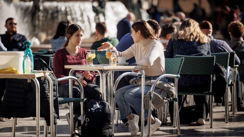 Varias personas disfrutan de un soleado día de invierno en una terraza en la ciudad de València.