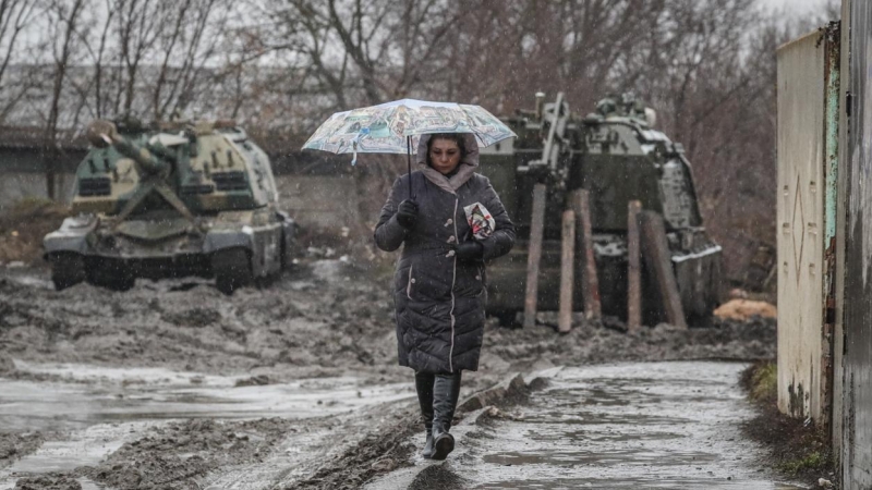Una mujer camina frente a vehículos blindados rusos en la estación de tren de la región de Rostov, Rusia, este 24 de febrero. Las tropas rusas lanzaron una importante operación militar en Ucrania tras semanas de intensa diplomacia y la imposición de sanci