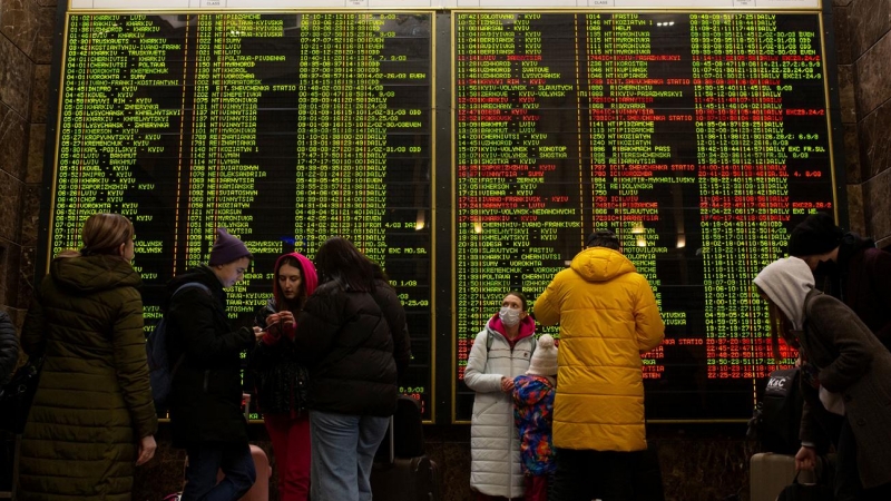 Cientos de personas consultan el horario del tren en la Estación Central de Ferrocarril para intentar salir de la ciudad de Kiev, Ucrania, tras la operación militar rusa.