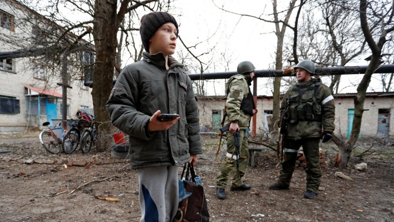 Un niño se para frente a un edificio de apartamentos, que según los lugareños fue dañado por los recientes bombardeos, en la ciudad de Yasynuvata (Yasinovataya), controlada por los separatistas prorrusos, en la región de Donetsk, Ucrania, este jueves.