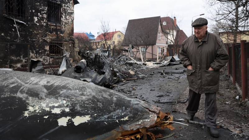 Un anciano camina entre los restos de un avión no identificado que se estrelló contra una casa en una zona residencial de Kiev, después de que Rusia lanzara una operación militar masiva contra Ucrania, este viernes 25 de febrero.