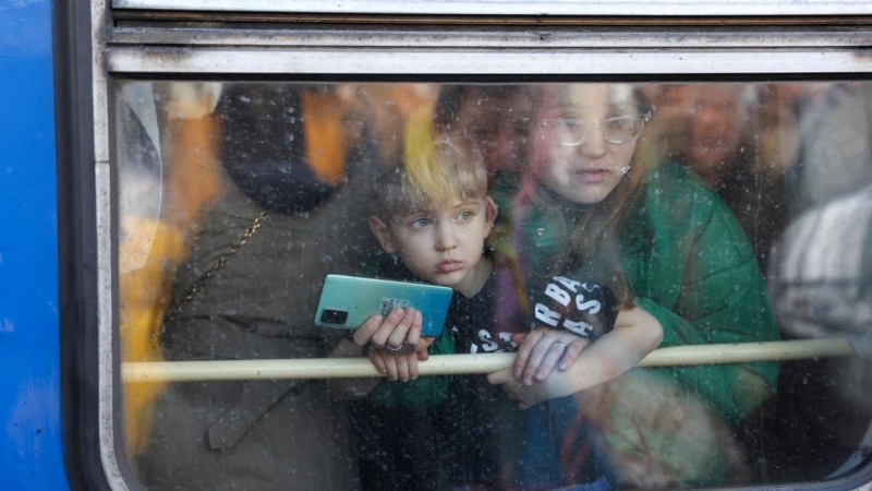 Una mujer y su hijo miran desde un tren de evacuación de Kiev a hacia la ciudad de Lviv (Leópolis) en la estación central de trenes de Kiev, en el segundo día la invasión rusa.