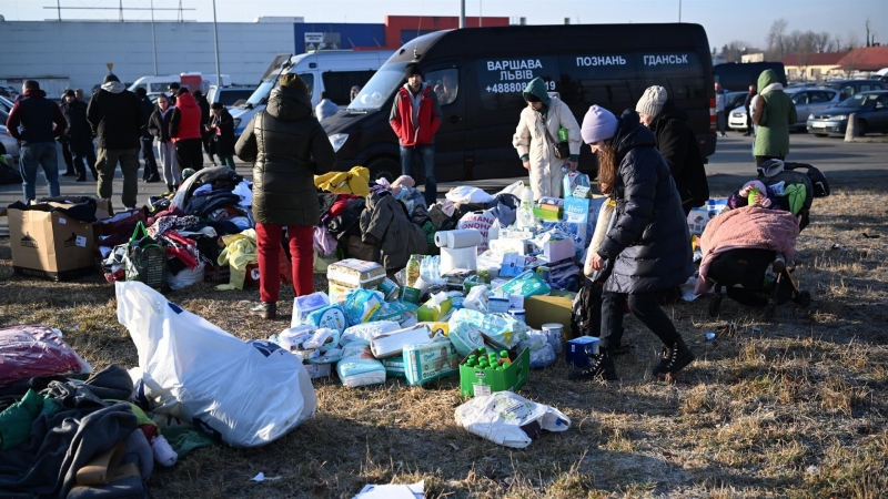La gente llega a un lugar de ayuda para refugiados de guerra de Ucrania organizado en un estacionamiento junto a una de las tiendas en Przemysl, Polonia, el 26 de febrero de 2022.