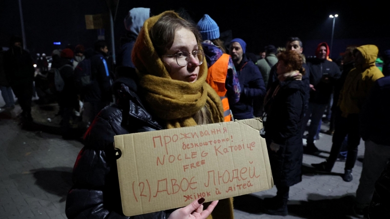 La gente espera en un estacionamiento a que lleguen los autobuses con refugiados para ayudar a organizar el transporte y el alojamiento a diferentes ciudades de Polonia y otros países después de que Rusia lanzó una operación militar masiva contra Ucrania,