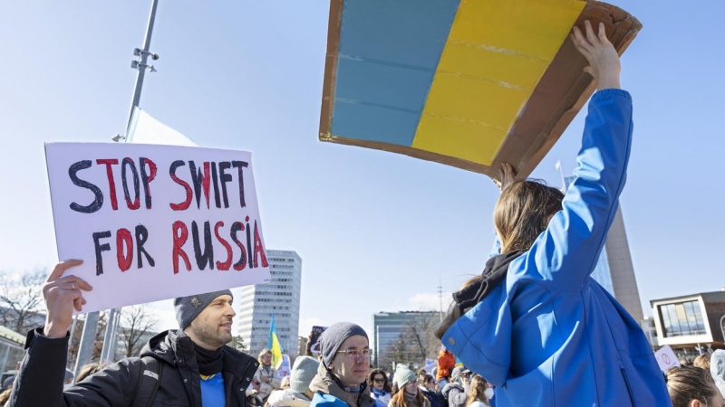 Un manifestante sostiene un cartel que dice 'Stop Swift for Russia' mientras protesta contra la operación militar masiva de Rusia contra Ucrania durante una manifestación en la sede de las Naciones Unidas en Ginebra, Suiza, el 26 de febrero de 2022.