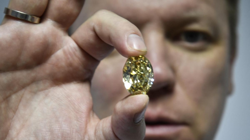 El subdirector de ventas de diamantes de Alrosa, Yevgeny Tsybukov, muestra un elegante diamante ovalado de color amarillo verdoso parduzco, en Moscú el 3 de julio de 2019.