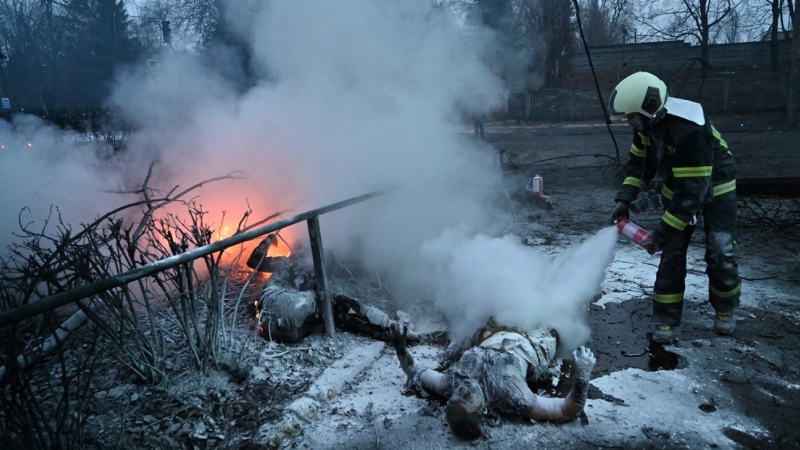 Un bombero extingue el fuego sobre los cuerpos de dos transeúntes que murieron en el bombardeo ruso contra la torre de televisión de Kiev el 1 de marzo.