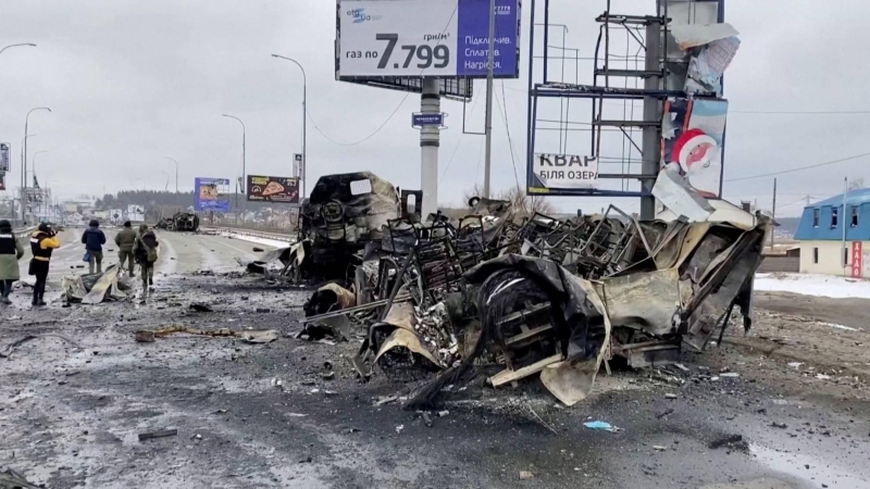 La gente pasa junto a un vehículo destruido en una carretera, en medio de la actual invasión de Ucrania por parte de Rusia, en Bucha, Ucrania este 2 de marzo de 2022.