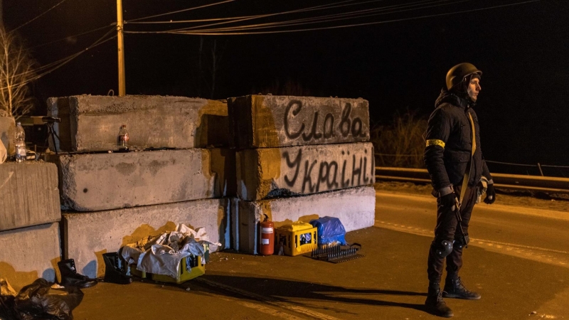 Un miembro de las Fuerzas de Defensa Territorial hace guardia junto a la barricada con el texto 'Gloria a Ucrania' en un puesto de control en el frente oriental de Kiev.