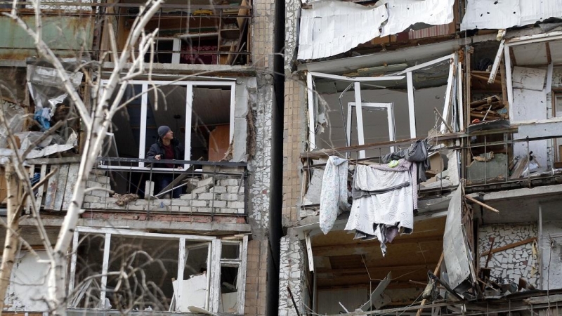 Un residente mira desde el frente destruido de una habitación en un edificio de varios pisos que resultó gravemente dañado como resultado de la explosión de un misil ruso después de que fue derribado sobre la ciudad por la defensa aérea ucraniana el 6 de