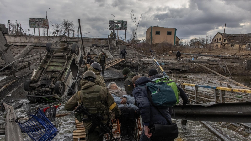 Militares ucranianos llevan a una anciana en silla de ruedas en una zona bombardeada en la ciudad de Irpin, en la región de Kiev, este 7 de marzo de 2022.