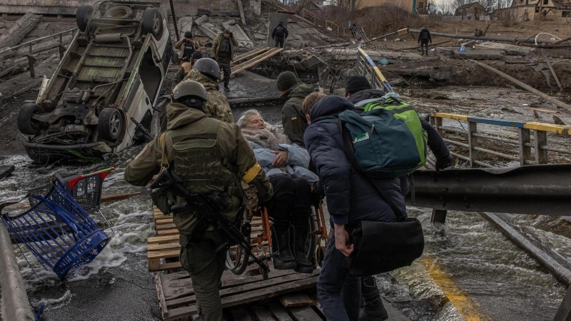Militares ucranianos llevan a una anciana en silla de ruedas en una zona bombardeada en la ciudad de Irpin, en la región de Kiev, este 7 de marzo de 2022.