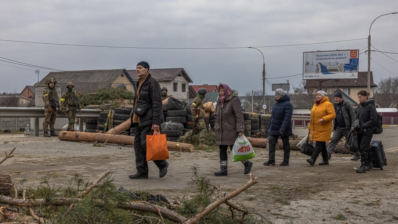 Varios residentes de la ciudad de Irpin, en la región de Kiev, huyen de la primera línea de fuego ante la mirada de militares ucranianos este 7 de marzo de 2022.